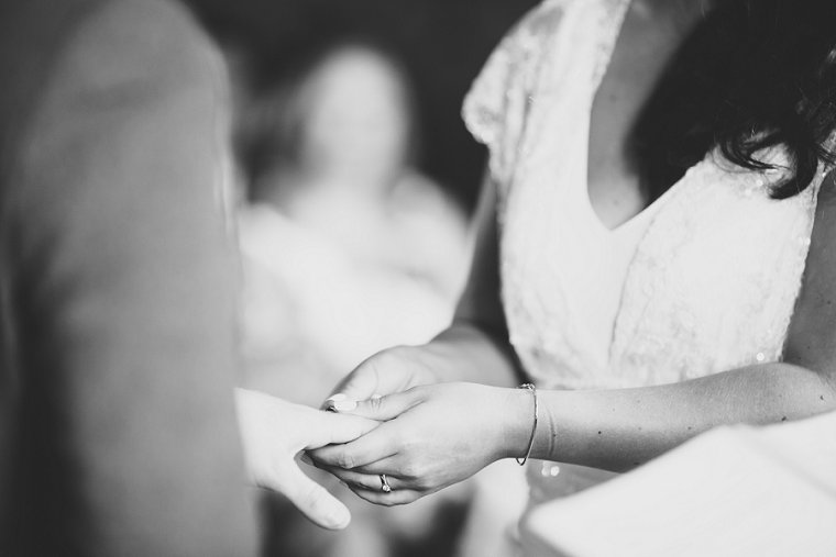 Bride putting wedding ring on the finger of groom